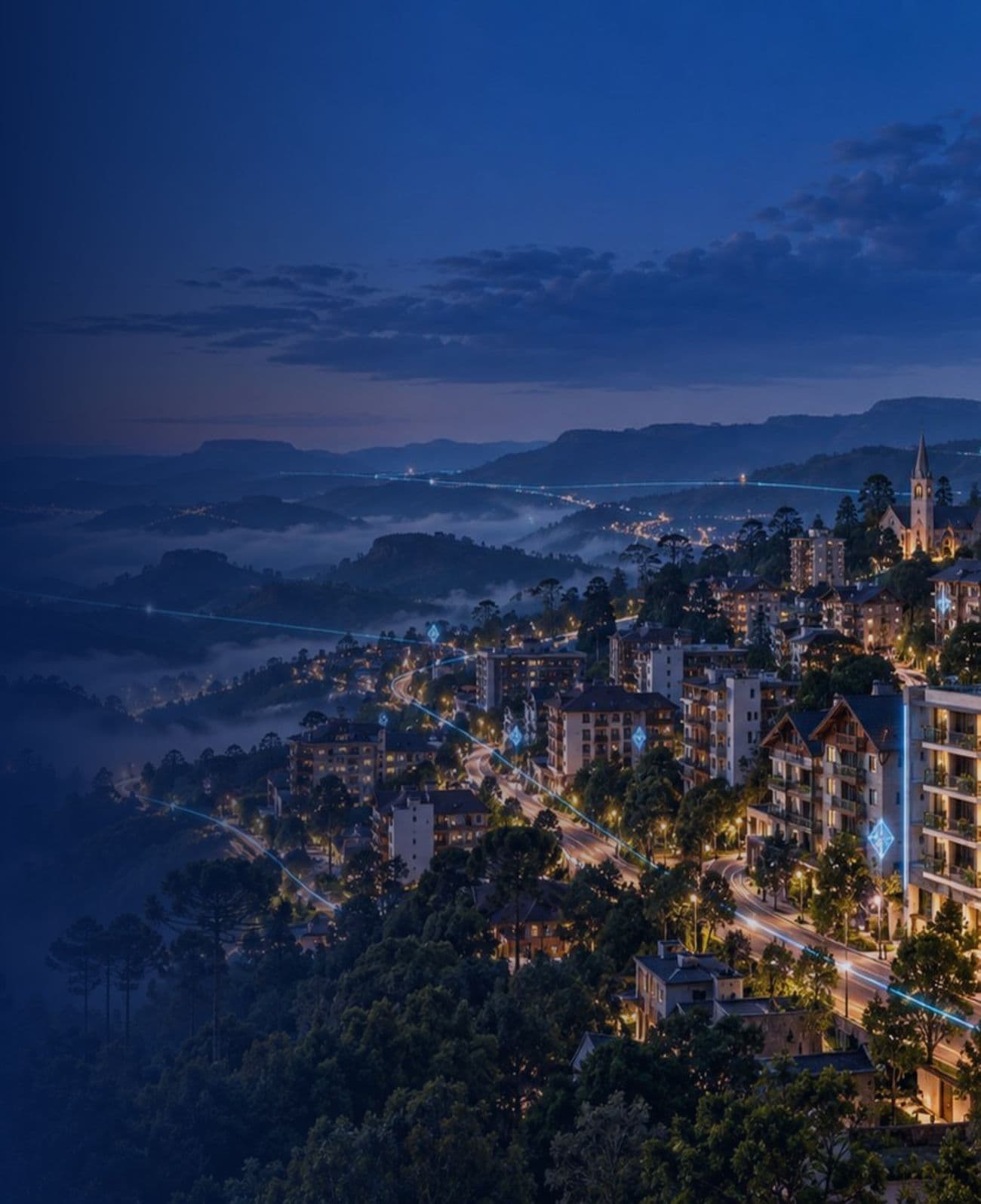Gramado à noite, vista do alto, com prédios iluminados entre as araucárias